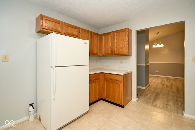 kitchen featuring an inviting chandelier, white refrigerator, light hardwood / wood-style floors, decorative light fixtures, and a textured ceiling