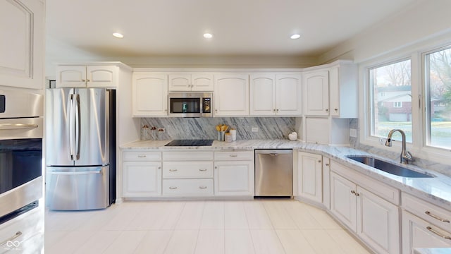 kitchen with white cabinets, light stone counters, sink, and appliances with stainless steel finishes