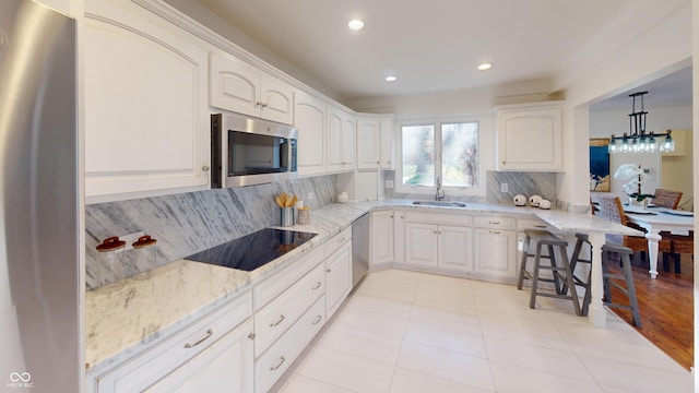 kitchen with backsplash, white cabinets, sink, light stone counters, and stainless steel appliances