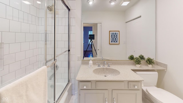 full bathroom with vanity, bath / shower combo with glass door, and toilet