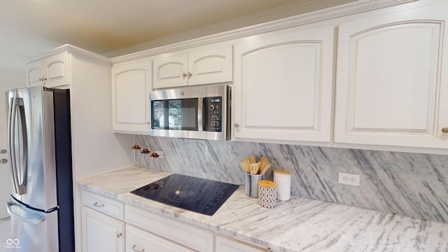 kitchen with light stone countertops, white cabinetry, stainless steel appliances, and tasteful backsplash