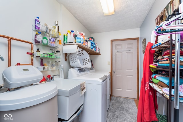 laundry area with washing machine and clothes dryer, light carpet, and a textured ceiling