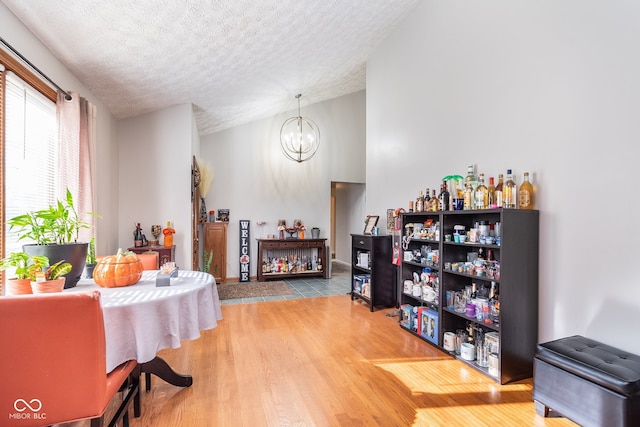 interior space with a notable chandelier, lofted ceiling, wood-type flooring, and a textured ceiling