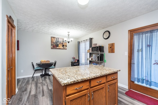 kitchen featuring a healthy amount of sunlight, dark hardwood / wood-style floors, a textured ceiling, decorative light fixtures, and a kitchen island