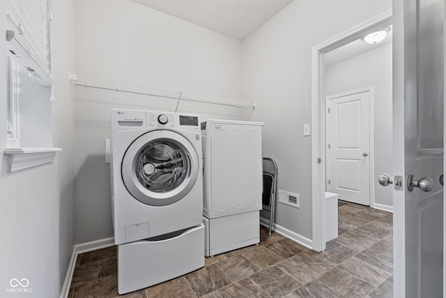 laundry room featuring a textured ceiling and washing machine and clothes dryer