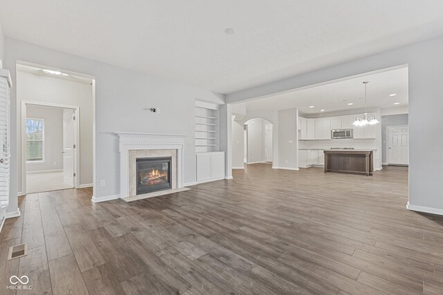 unfurnished living room with built in shelves and hardwood / wood-style flooring