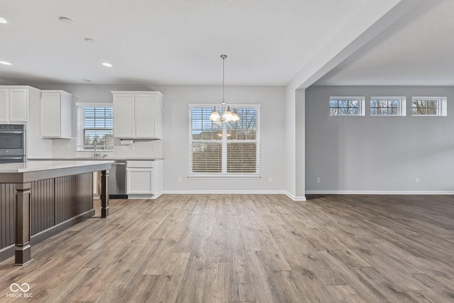 kitchen with decorative backsplash, decorative light fixtures, a notable chandelier, white cabinets, and light hardwood / wood-style floors