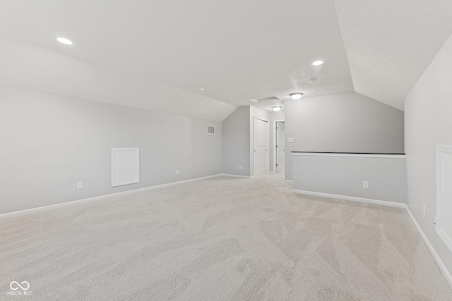 bonus room with light colored carpet, lofted ceiling, and a textured ceiling