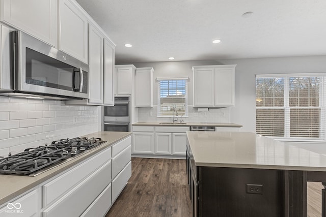 kitchen featuring gas cooktop, dark wood-type flooring, sink, a center island, and white cabinetry