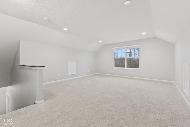 additional living space featuring light colored carpet, lofted ceiling, and a textured ceiling