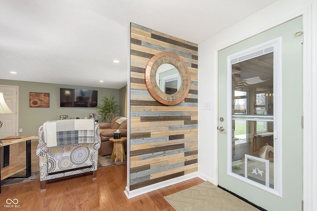 entryway featuring an accent wall, recessed lighting, wood finished floors, and wood walls