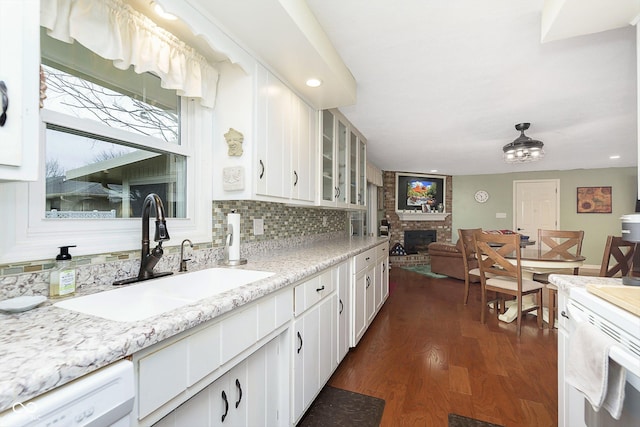 kitchen featuring dark wood-style flooring, a sink, glass insert cabinets, dishwasher, and tasteful backsplash