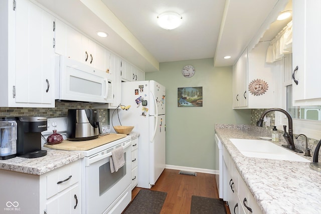 kitchen featuring backsplash, dark wood finished floors, light countertops, white appliances, and a sink