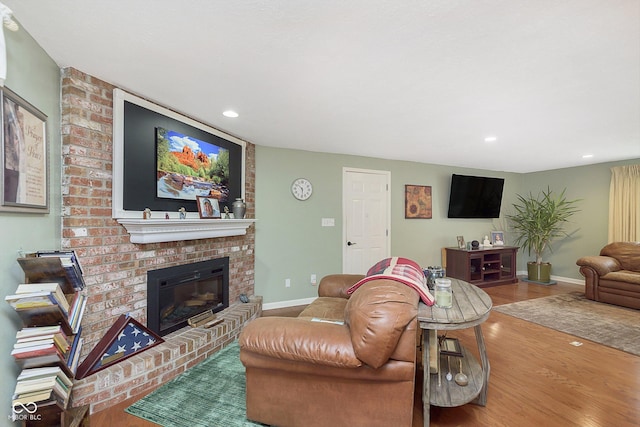 living room featuring recessed lighting, a brick fireplace, baseboards, and wood finished floors