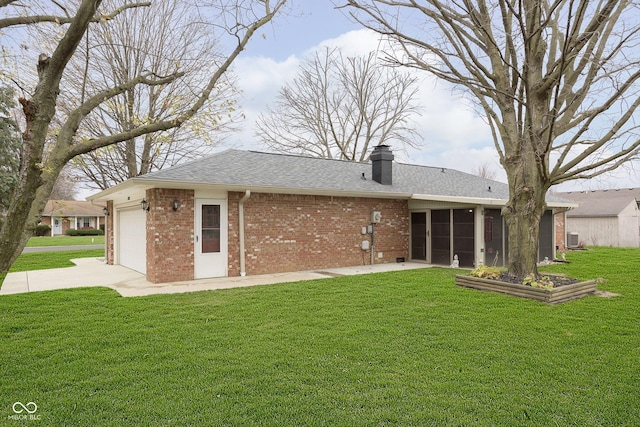 rear view of property with brick siding, roof with shingles, a lawn, a chimney, and an attached garage