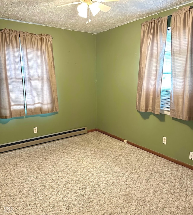 empty room with plenty of natural light, ceiling fan, a textured ceiling, and a baseboard heating unit