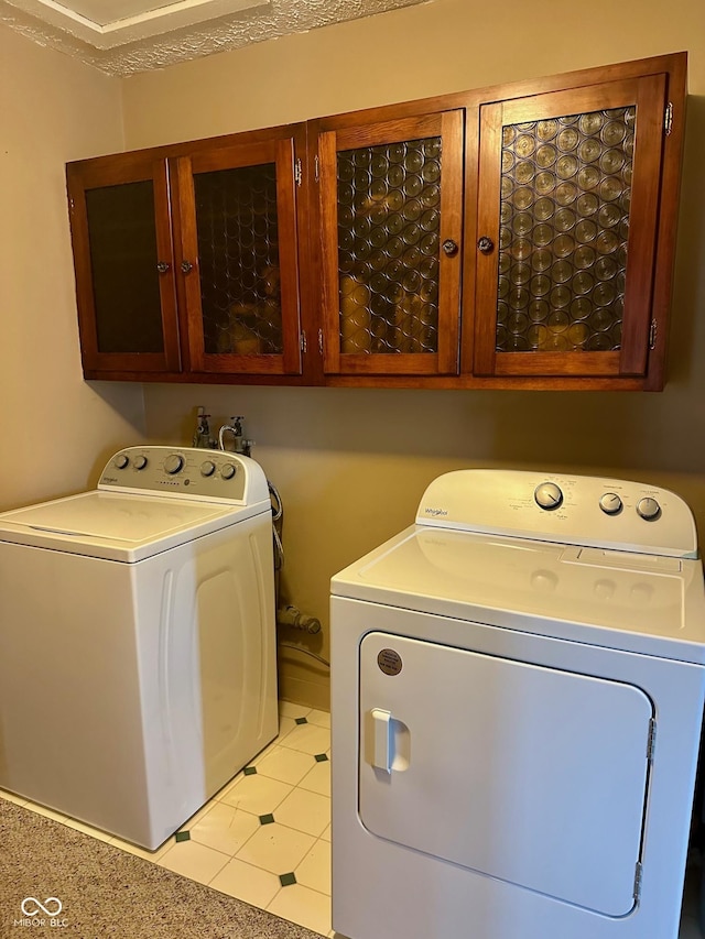 clothes washing area featuring cabinets, a textured ceiling, and washing machine and dryer