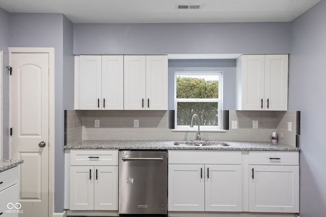 kitchen featuring sink, stainless steel dishwasher, tasteful backsplash, light stone counters, and white cabinetry