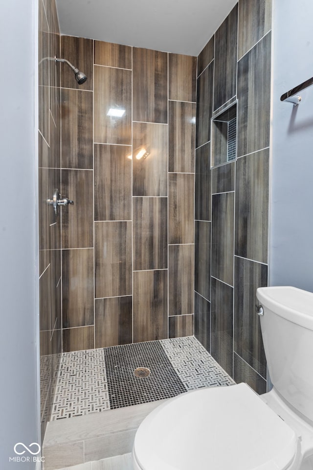 bathroom with a tile shower and toilet