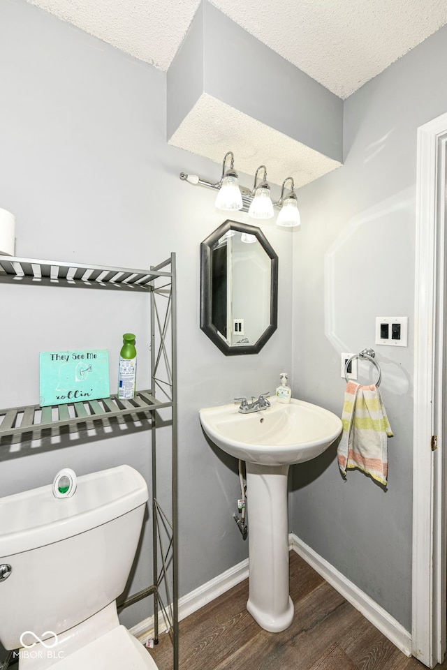 bathroom featuring hardwood / wood-style floors, toilet, sink, and a textured ceiling