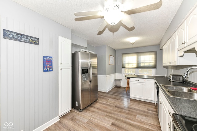 kitchen featuring white cabinetry, light hardwood / wood-style flooring, a textured ceiling, and appliances with stainless steel finishes