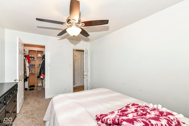 carpeted bedroom with a textured ceiling, a spacious closet, and ceiling fan