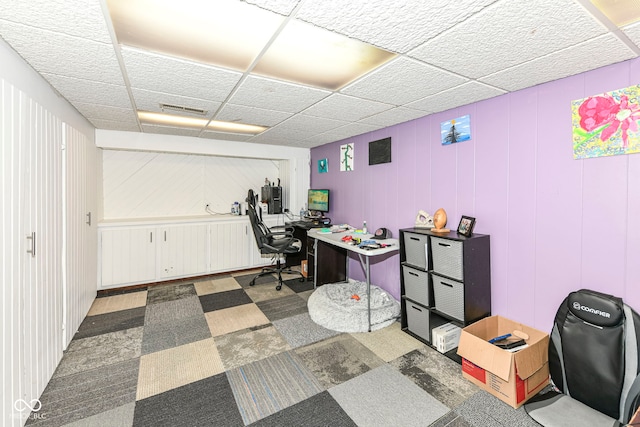 office featuring a drop ceiling and wood walls