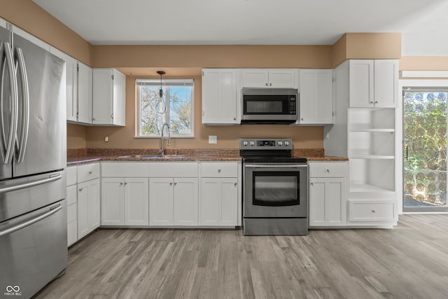 kitchen with white cabinets, light wood-type flooring, stainless steel appliances, and sink