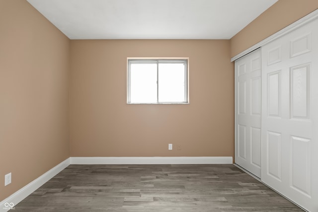 unfurnished bedroom with dark hardwood / wood-style floors and a closet