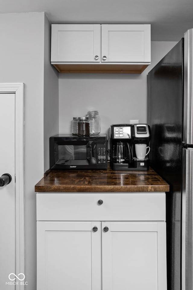 bar with stainless steel fridge and white cabinetry