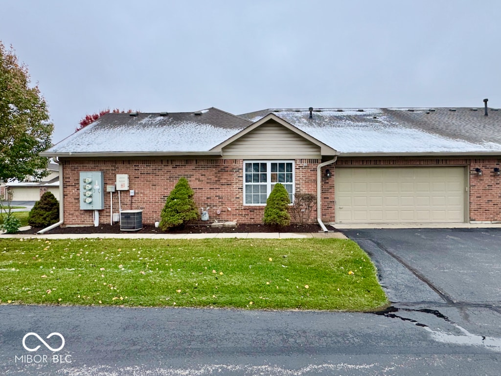 view of front of property featuring a garage, a front lawn, and central air condition unit