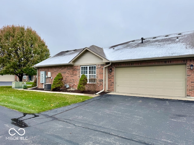 view of front of home with a garage, a front yard, and central AC