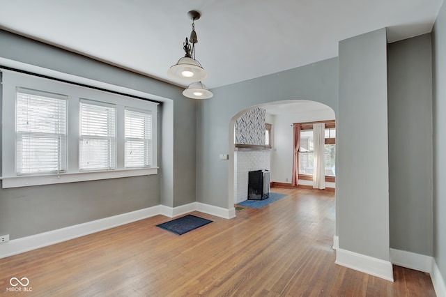 unfurnished living room with a fireplace, plenty of natural light, and wood-type flooring