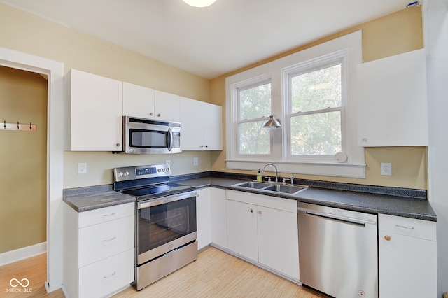 kitchen with white cabinets, appliances with stainless steel finishes, light wood-type flooring, and sink