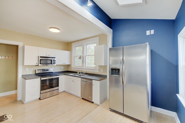 kitchen featuring white cabinets, appliances with stainless steel finishes, lofted ceiling, and sink