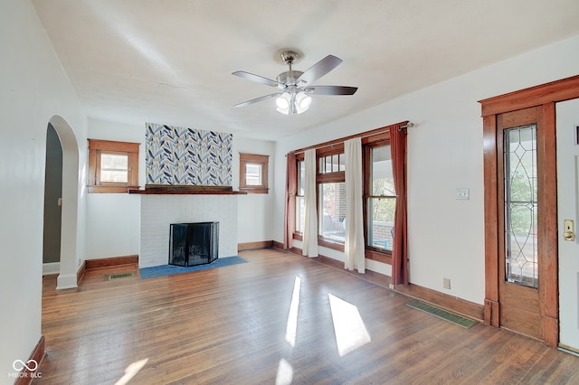 unfurnished living room featuring ceiling fan, hardwood / wood-style floors, and a brick fireplace