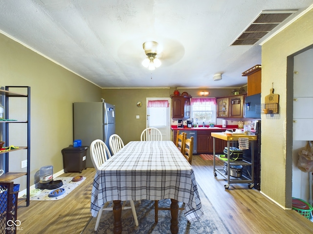 dining area featuring a textured ceiling, light hardwood / wood-style flooring, ceiling fan, and crown molding