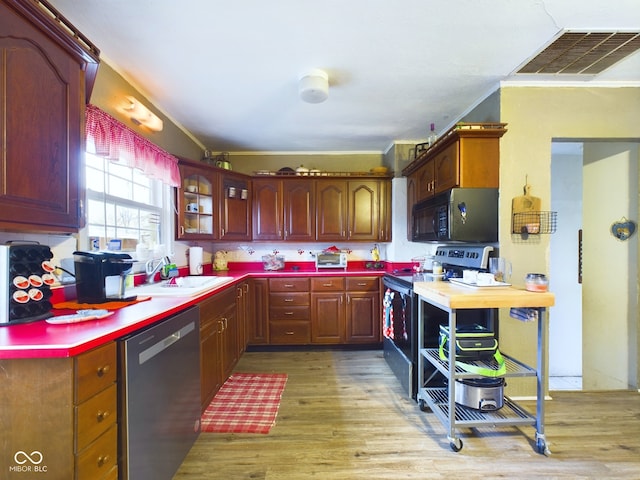 kitchen featuring black appliances, light hardwood / wood-style floors, ornamental molding, and sink