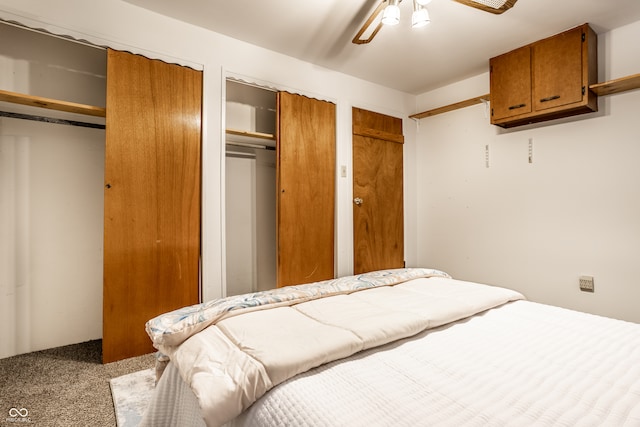 bedroom featuring carpet, ceiling fan, and multiple closets