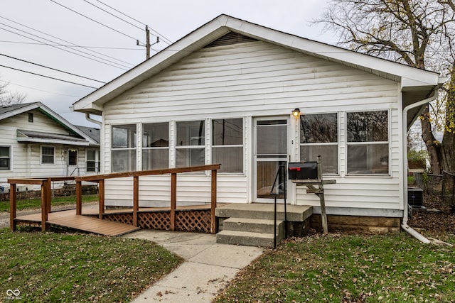 bungalow-style home with a sunroom, cooling unit, and a front yard