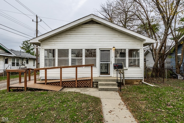 bungalow-style house with a sunroom, a front lawn, and a deck