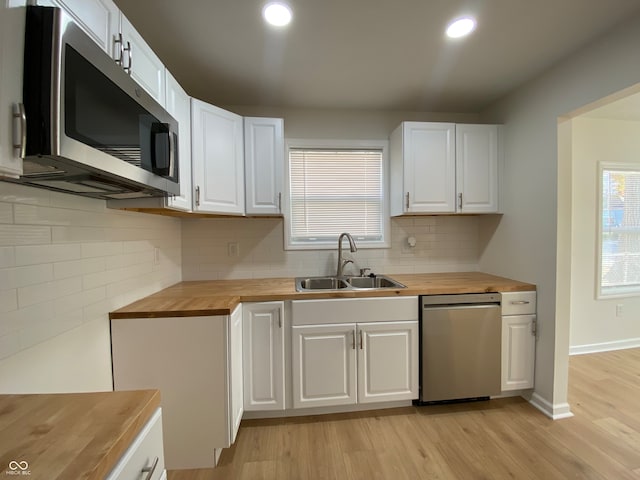 kitchen featuring light hardwood / wood-style floors, stainless steel appliances, sink, butcher block countertops, and white cabinetry