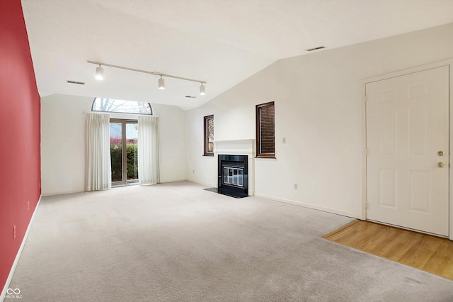 unfurnished living room with track lighting, vaulted ceiling, and light wood-type flooring