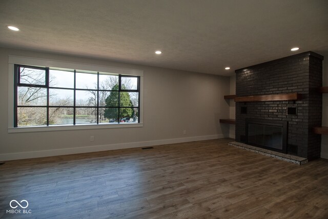 unfurnished living room featuring a fireplace and dark wood-type flooring