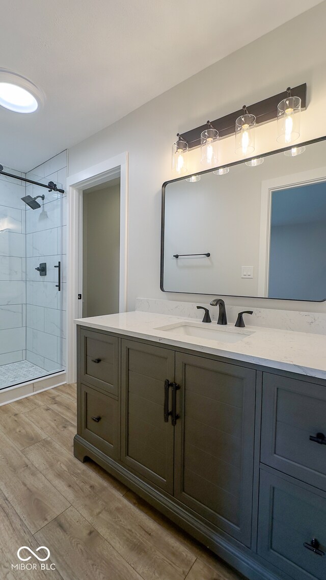 bathroom featuring hardwood / wood-style floors, vanity, and a shower with shower door