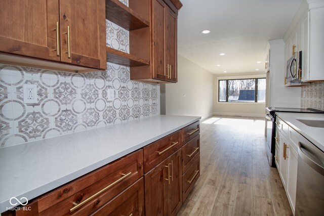 kitchen featuring tasteful backsplash, white cabinetry, stainless steel appliances, and light hardwood / wood-style floors