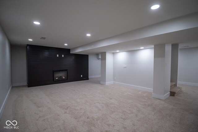 basement featuring a large fireplace and light colored carpet