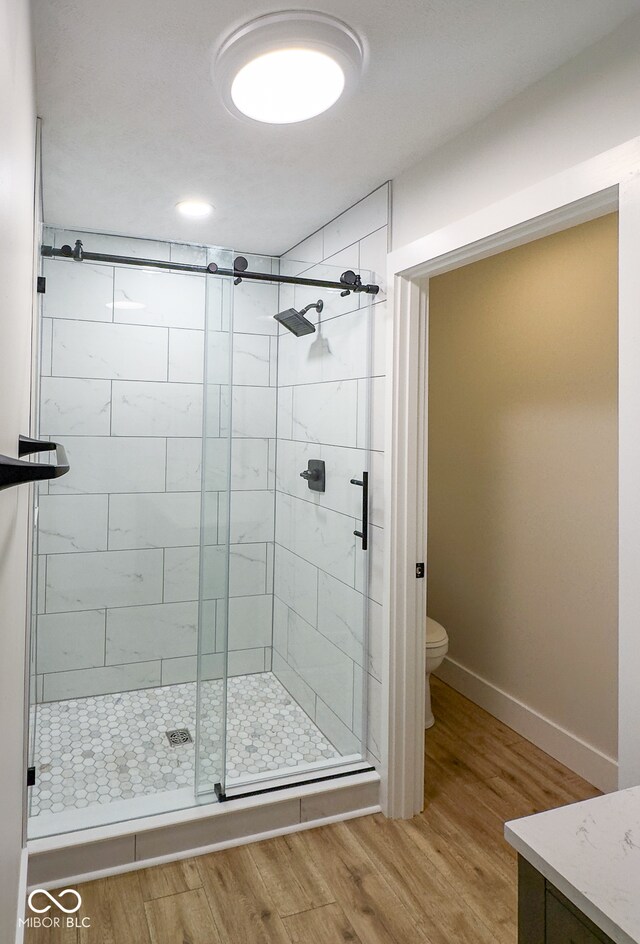 bathroom featuring wood-type flooring, toilet, and an enclosed shower