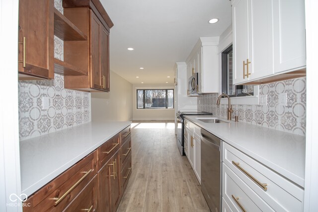 kitchen with white cabinets, sink, light hardwood / wood-style flooring, appliances with stainless steel finishes, and tasteful backsplash