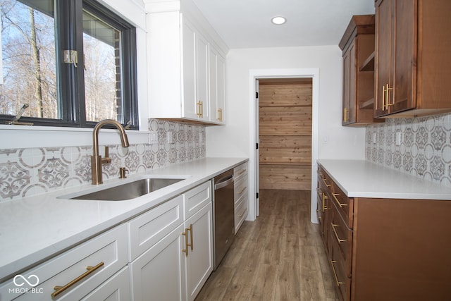 kitchen featuring decorative backsplash, light hardwood / wood-style flooring, white cabinetry, and stainless steel dishwasher